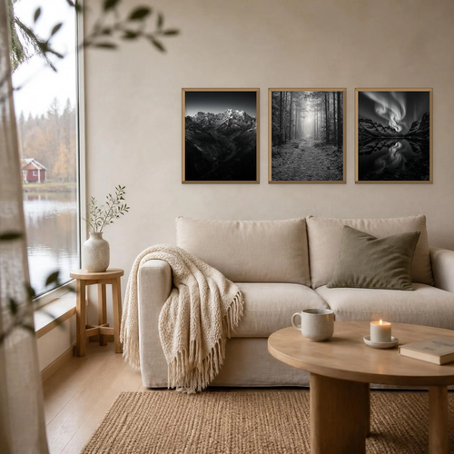 Black and white northern lights poster in a light oak frame, hanging as one of three posters above a linen sofa